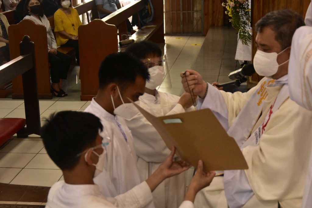 Br. Reymar Macadagdag kneels as he receives the OAR Cross necklace.