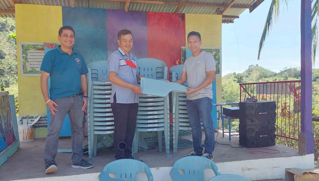 One Thomasian Family. (L-R) Fray Vicente Ramon, Jr., OAR, CEDO director, poses <br/> as Mr. Johnny Engada, Ansulag ES head teacher, receives the chairs from Fray Joel Alve, OAR, CST-R director-principal.